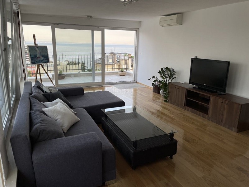 Pokój dzienny z widokiem na taras i morze.