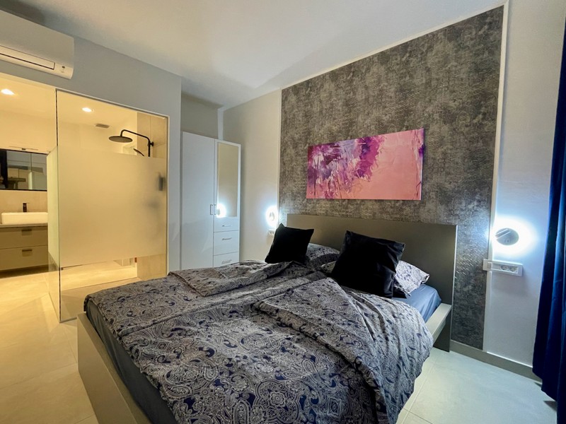 Widok wnętrza łazienki ze szklaną zasłoną prysznicową oraz widok na jasny pokój w mieszkaniu na sprzedaż w Zadarze w Chorwacji