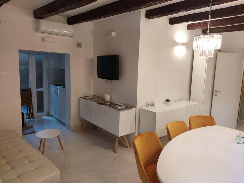 Klimatyzowany salon z telewizorem i jadalnią oraz aneks kuchenny.