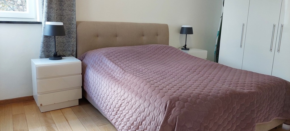 Sypialnia z dużym podwójnym łóżkiem i minimalistycznym wystrojem w Opatiji