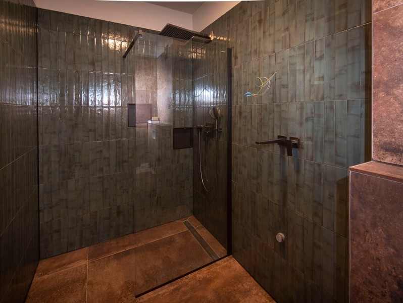 Łazienka z przestronną kabiną prysznicową w nowoczesnym mieszkaniu na sprzedaż w Splicie w Chorwacji, z ciemnymi kafelkami.