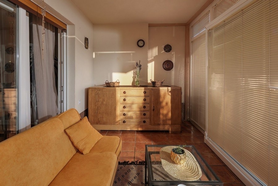 Zalany słońcem ogród zimowy chorwackiego mieszkania z żółtą sofą.