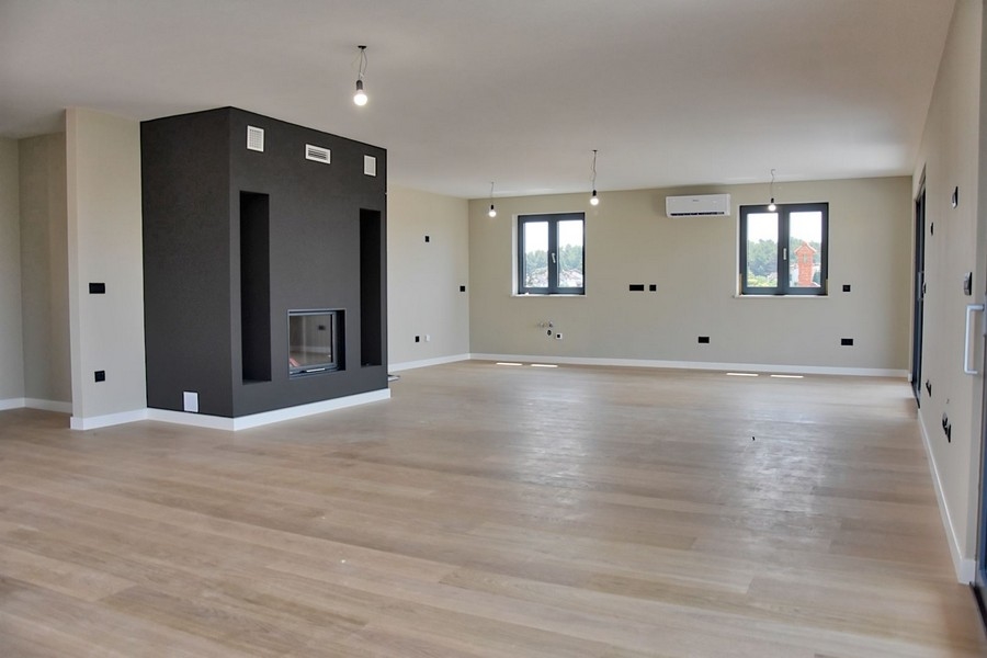 Współczesny salon w penthousie na sprzedaż na Istrii, z kominkiem i widokiem na morze.