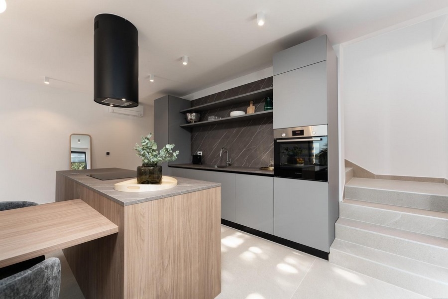 Nowoczesna kuchnia z centralną wyspą kuchenną i wysokiej jakości urządzeniami do zabudowy w luksusowym apartamencie na Istrii