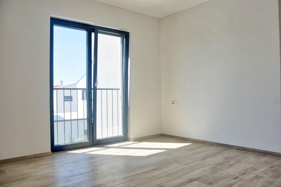 Jasna sypialnia z drzwiami balkonowymi i podłogą laminowaną, część oferty nieruchomości w Porec