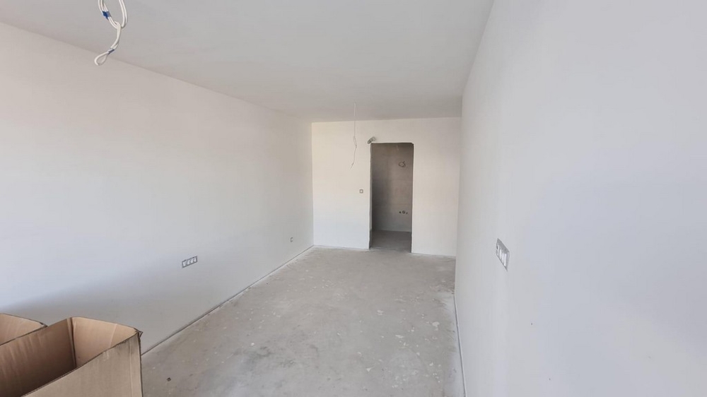 Pusty pokój w mieszkaniu w Chorwacji z jasnymi ścianami i betonową podłogą.