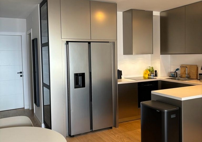 Nowoczesna kuchnia z lodówką ze stali nierdzewnej i ciemnymi szafkami, część nieruchomości w Rijece w Chorwacji.