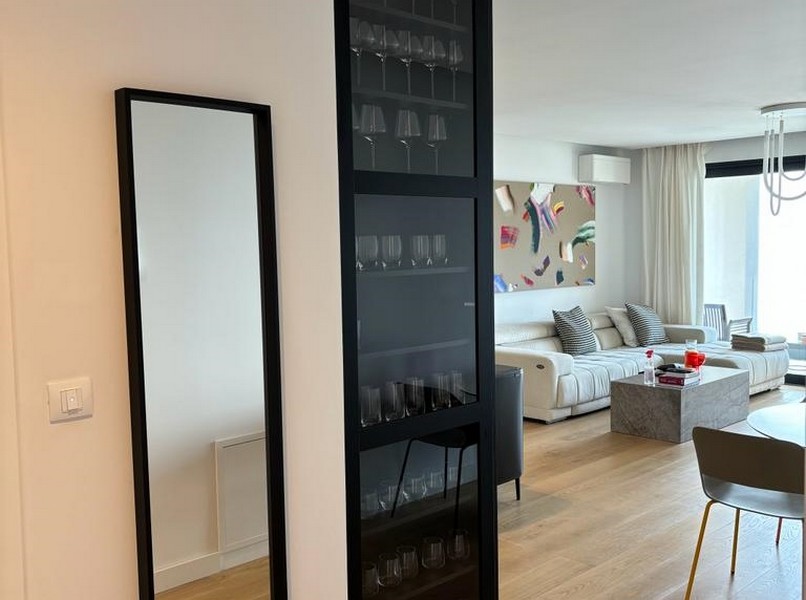Elegancki stojak na wino obok drzwi z czarnego szkła, fragment mieszkania na sprzedaż w Rijece w Chorwacji.