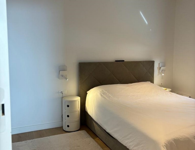 Minimalistyczna sypialnia z dużym łóżkiem i stolikiem nocnym, część nieruchomości w Rijece w Chorwacji.