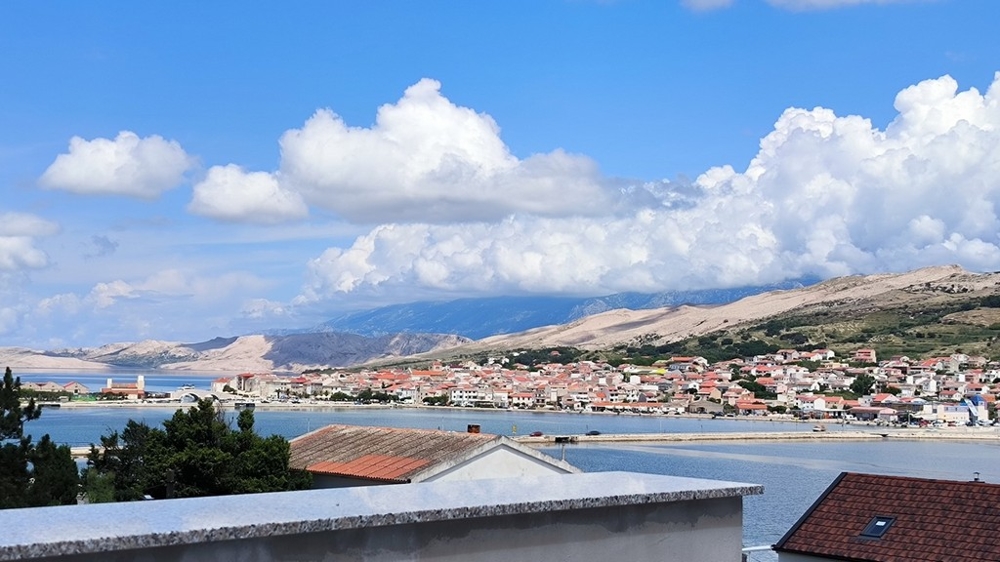 Widok zewnętrzny na parking mieszkania na sprzedaż w Pag w Chorwacji, ze żwirową ścieżką