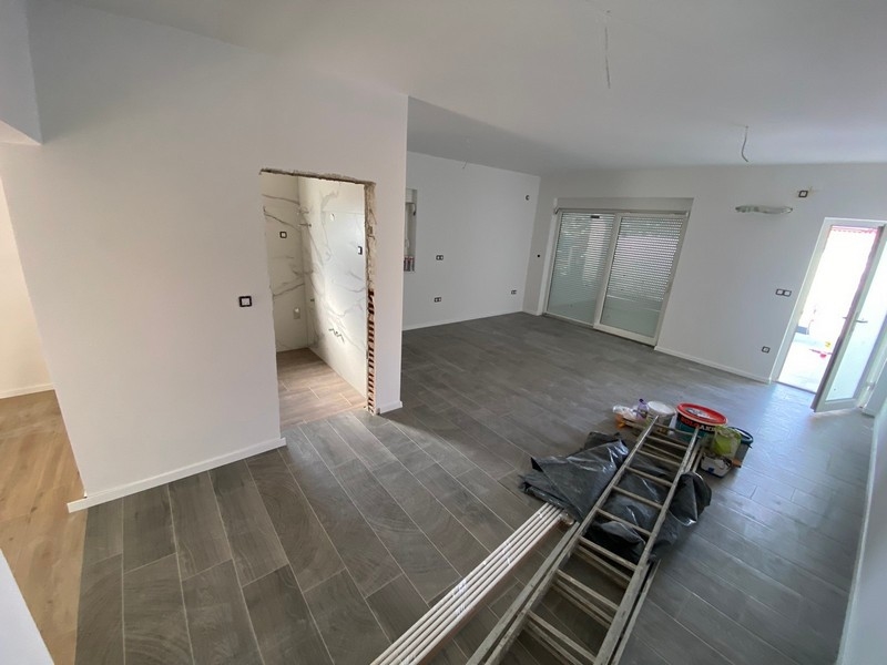 Pusty salon z szarą podłogą wyłożoną kafelkami w mieszkaniu na sprzedaż w Pag w Chorwacji