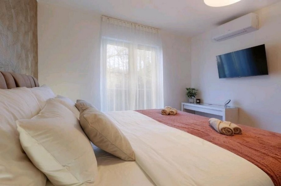 Sypialnia z dużym łóżkiem i telewizorem w mieszkaniu, na sprzedaż w pobliżu Opatiji w Chorwacji