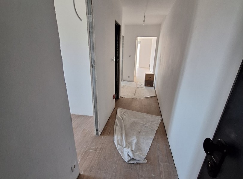 Przedpokój w nowym mieszkaniu, pokrycie ochronne na podłodze, stan surowy budynku, jasne ściany, drewniana podłoga, drzwi i pokoje w tle, oferta Panorama Scouting w Chorwacji.