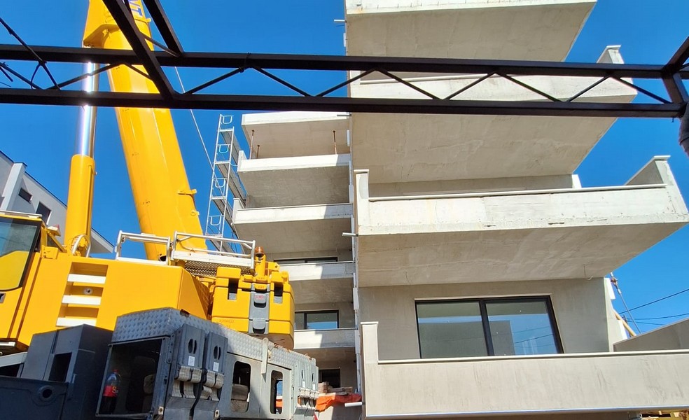 Praca dźwigiem na nowym budynku apartamentowca z widokiem na otaczającą architekturę w Chorwacji, oferowaną przez Panorama Scouting