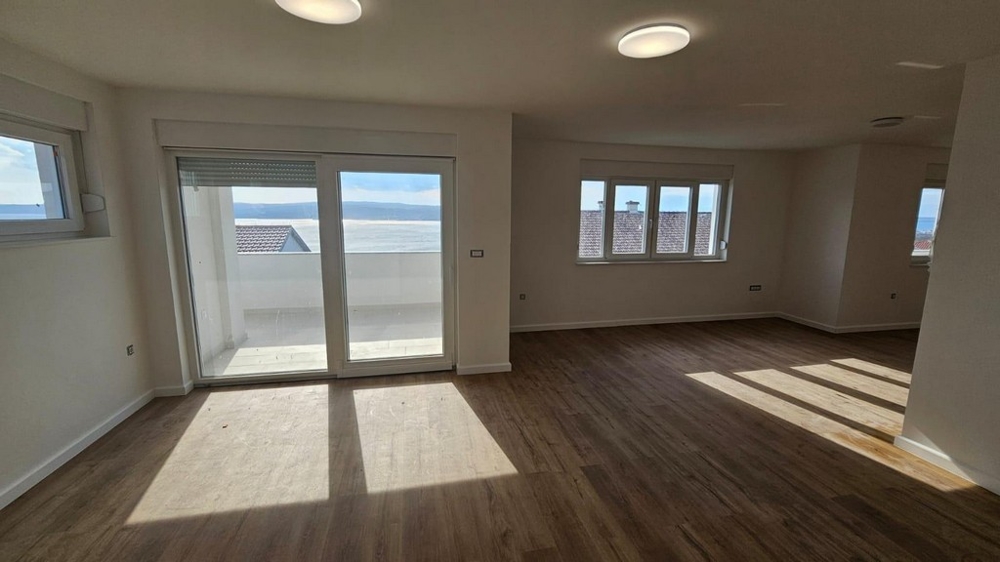 Jasny salon z drewnianą podłogą w mieszkaniu na sprzedaż w Crikvenicy w Chorwacji, z dostępem do balkonu i widokiem na morze
