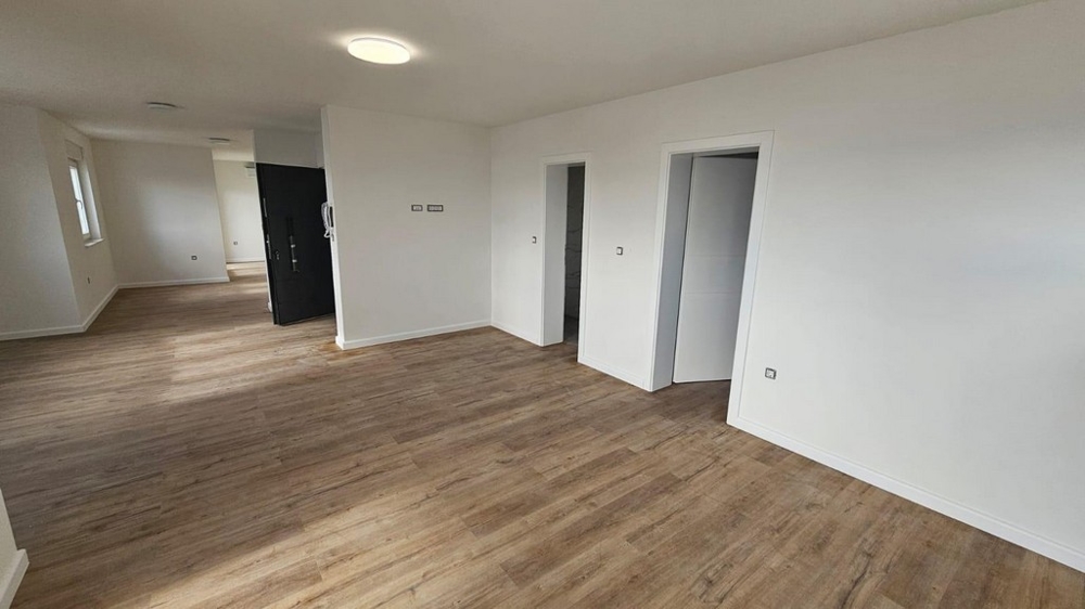 Przestronny salon na sprzedaż mieszkania w Crikvenicy w Chorwacji, z drewnianymi podłogami i białymi ścianami