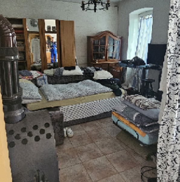 Pokój dzienny z kilkoma sofami i piecem opalanym drewnem, lustrem i telewizorem