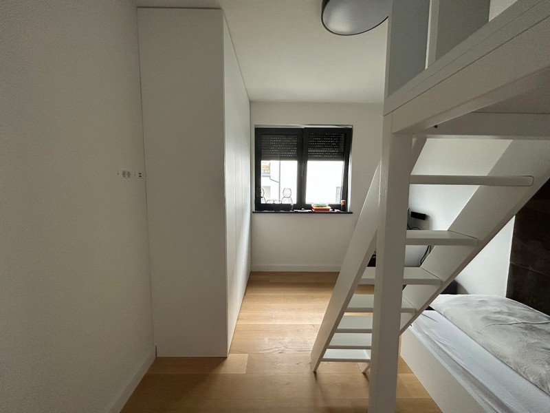 Druga sypialnia z łóżkiem na poddaszu i miejscem do pracy w nowoczesnym apartamencie w Rijece w Chorwacji.