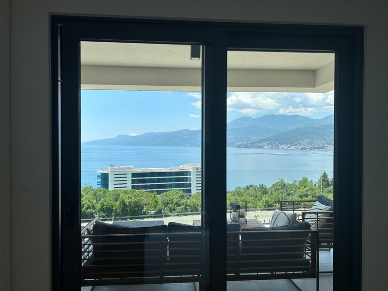 Widok przez otwarte drzwi patio nowoczesnego apartamentu z widokiem na zatokę Kvarner.