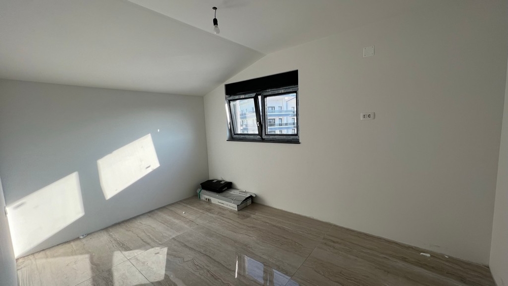 Minimalistycznie zaprojektowany salon z jasnymi podłogami wyłożonymi kafelkami, pasujący do nowoczesnych nieruchomości w Chorwacji.