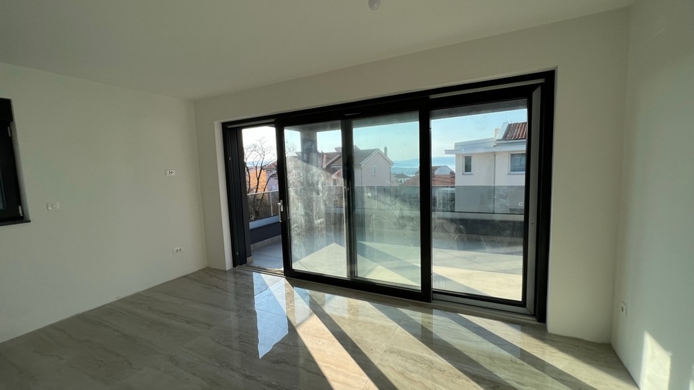 Jasny salon z oknami sięgającymi od podłogi do sufitu wpisuje się w nowoczesną koncepcję nieruchomości na wyspie Krk.