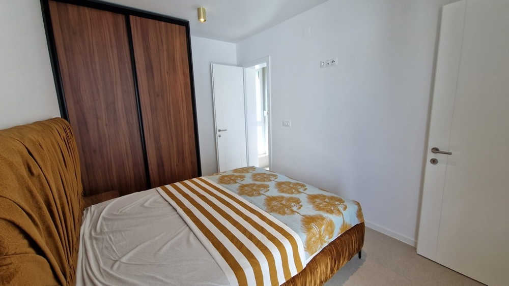 Sypialnia mieszkania w Novalji na wyspie Pag, z pościelą w paski i drewnianymi elementami, nieruchomość w Chorwacji