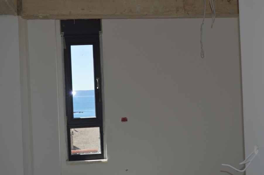 Wąskie okno w niewykończonym mieszkaniu z widokiem na morze.