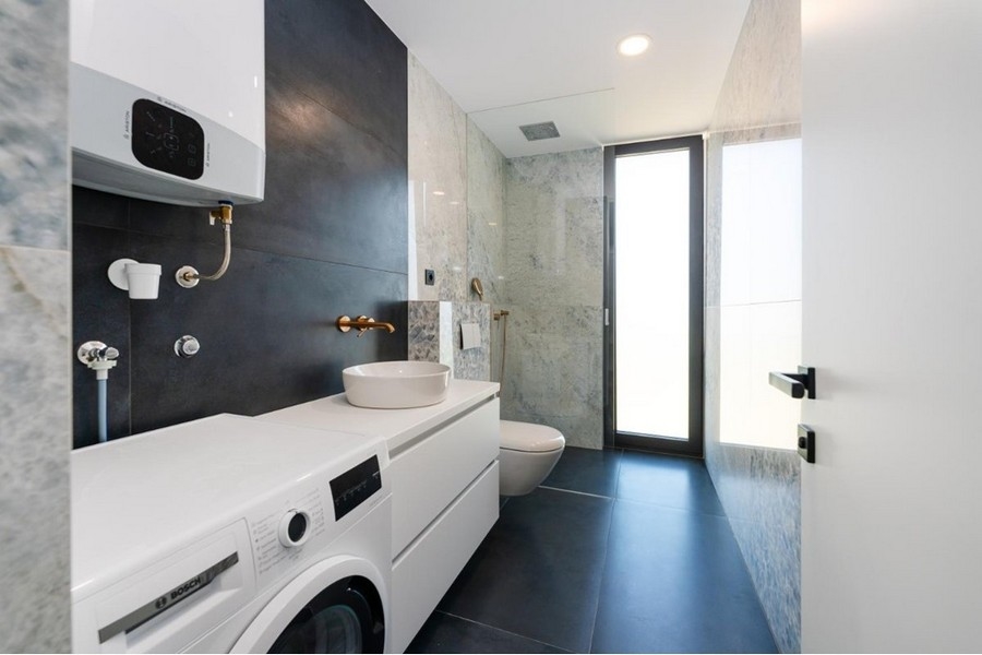 Łazienka z pralką, białą umywalką, przeszklonym prysznicem