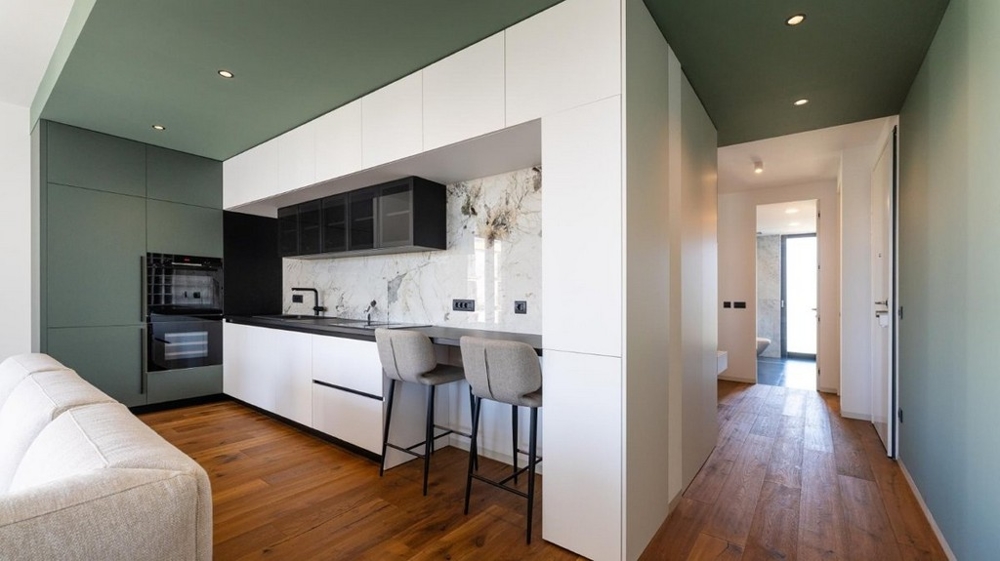 Kuchnia ze stołkami barowymi, przejście do przedpokoju, podłoga drewniana