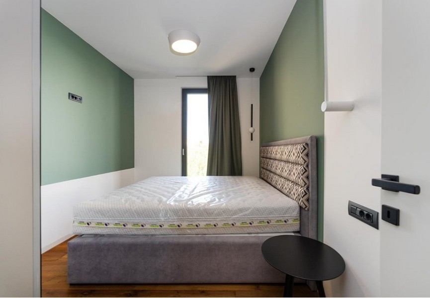 Sypialnia z zielonymi i białymi ścianami, szara rama łóżka