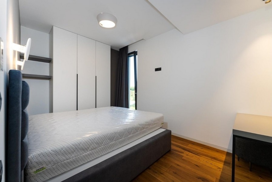 Przestronna sypialnia z dużym oknem i wbudowanymi szafami