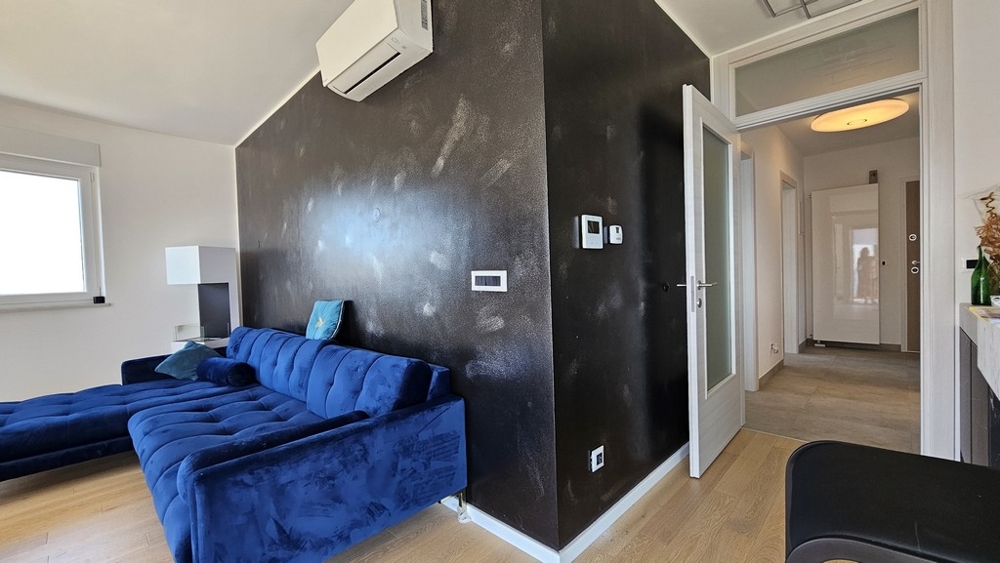 Pokój dzienny z niebieską kanapą, klimatyzacją i czarną ścianą