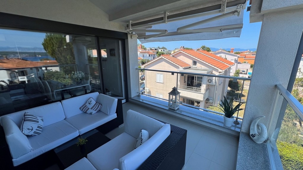 Taras z widokiem na morze i sąsiednie domy, wyposażony w białe sofy i morskie poduszki.