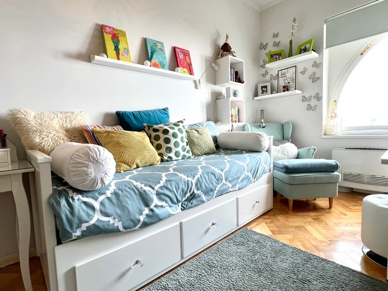 Pokój gościnny z leżanką, ozdobnymi poduszkami i przytulną częścią wypoczynkową