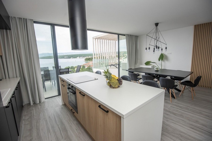 Nowoczesna kuchnia ze stołem jadalnym i widokiem na morze.