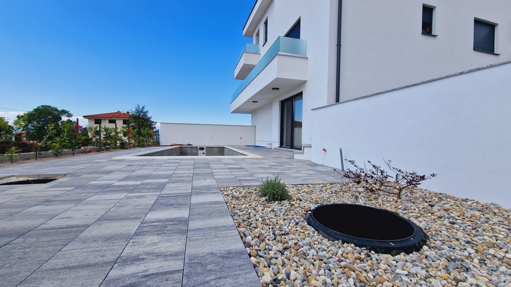 Na zewnątrz budynku podłoga wyłożona kafelkami i podsypka żwirowa