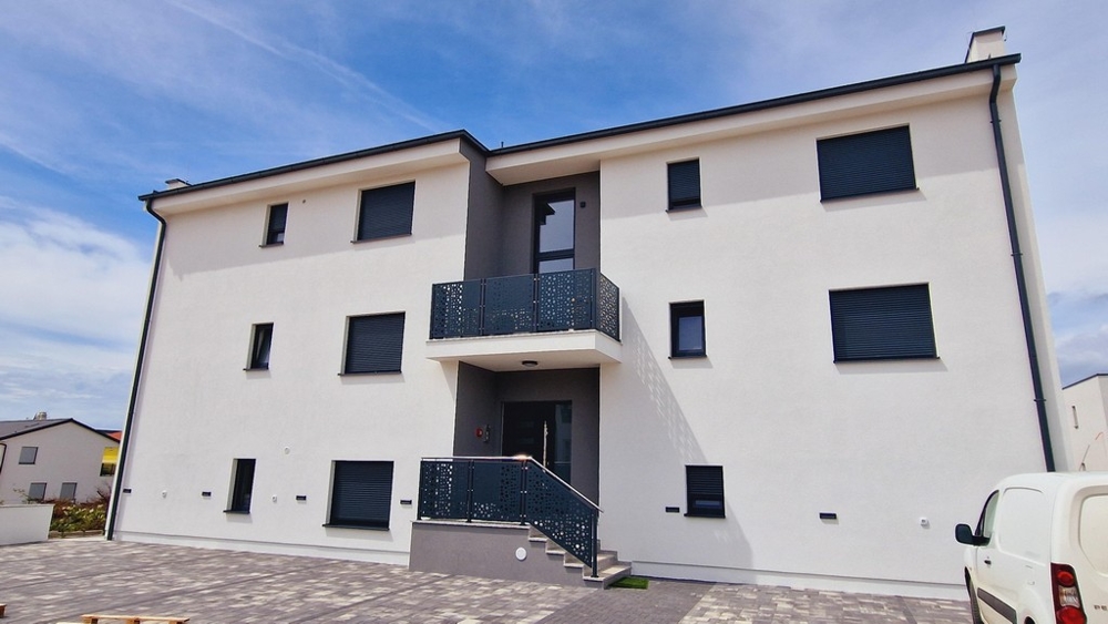 Widok z przodu nowoczesnego budynku z białymi ścianami i balkonami z metalowymi balustradami