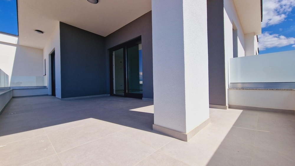 Duży, nowoczesny taras z białymi kolumnami i szklanymi balustradami