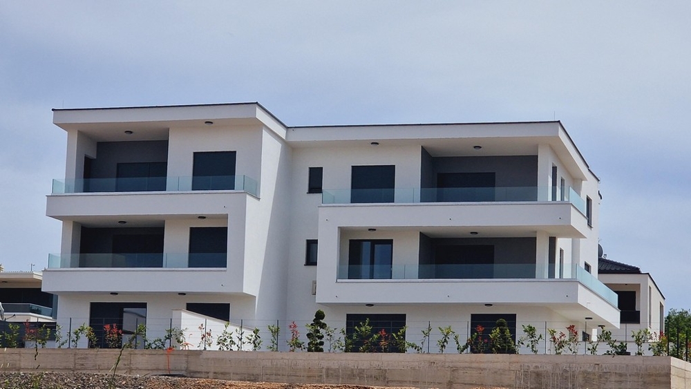 Nowoczesny, trzykondygnacyjny zespół mieszkaniowy z balkonami i szklanymi balustradami