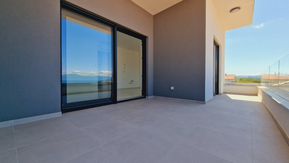 Taras z podłogą wyłożoną kafelkami i szklanymi balustradami, widok na morze i okolicę