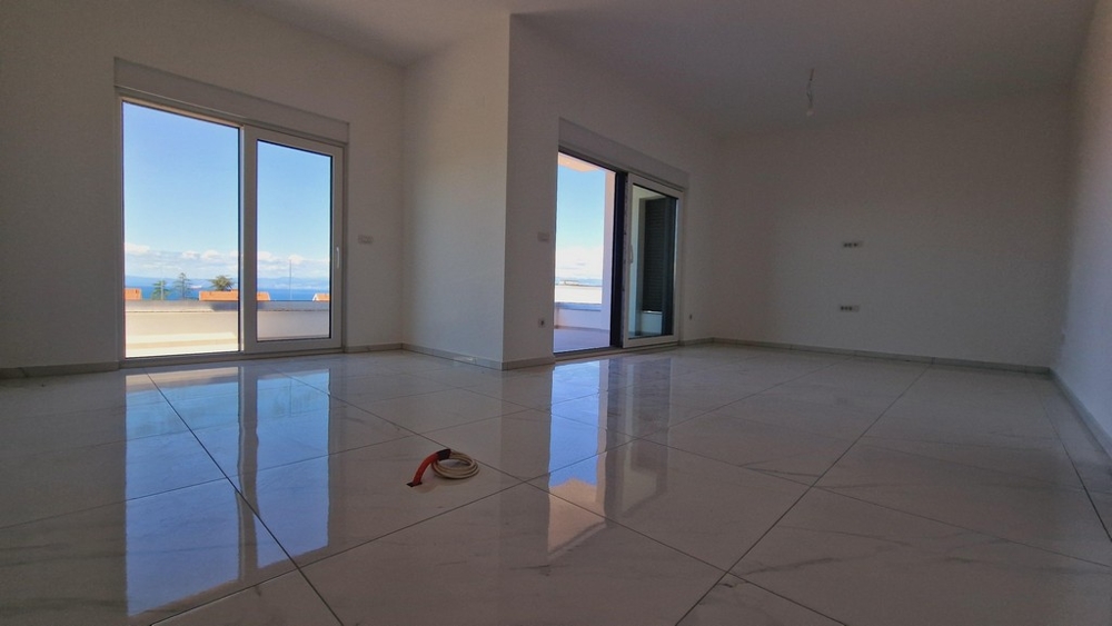 Przestronny i jasny salon z dwoma dużymi oknami prowadzącymi na taras