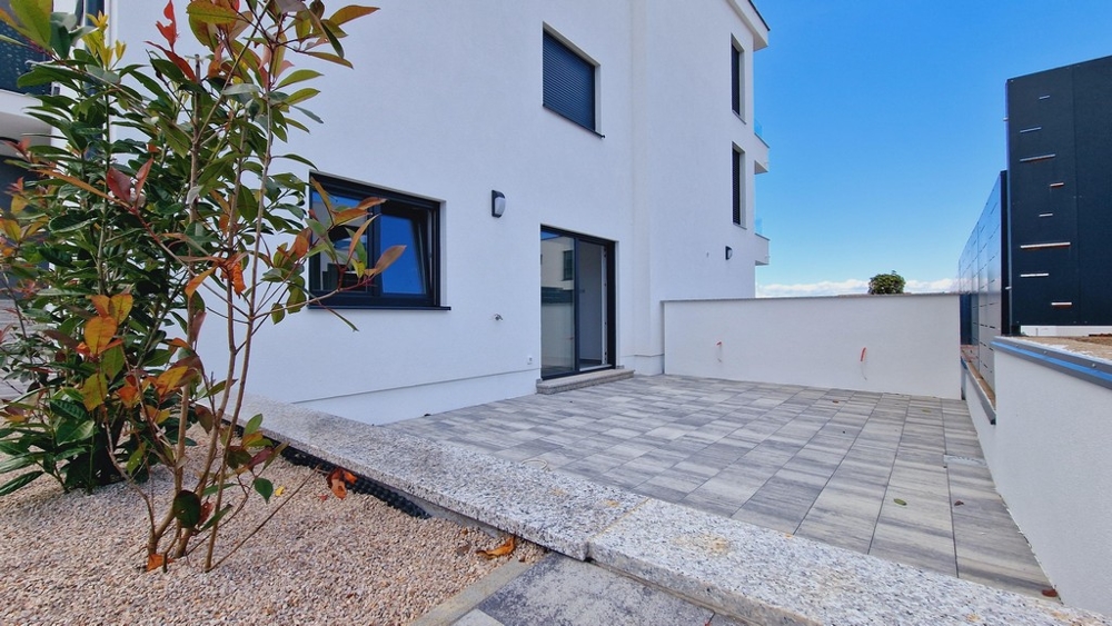 Część zewnętrzna mieszkania na parterze z utwardzonym tarasem i roślinami