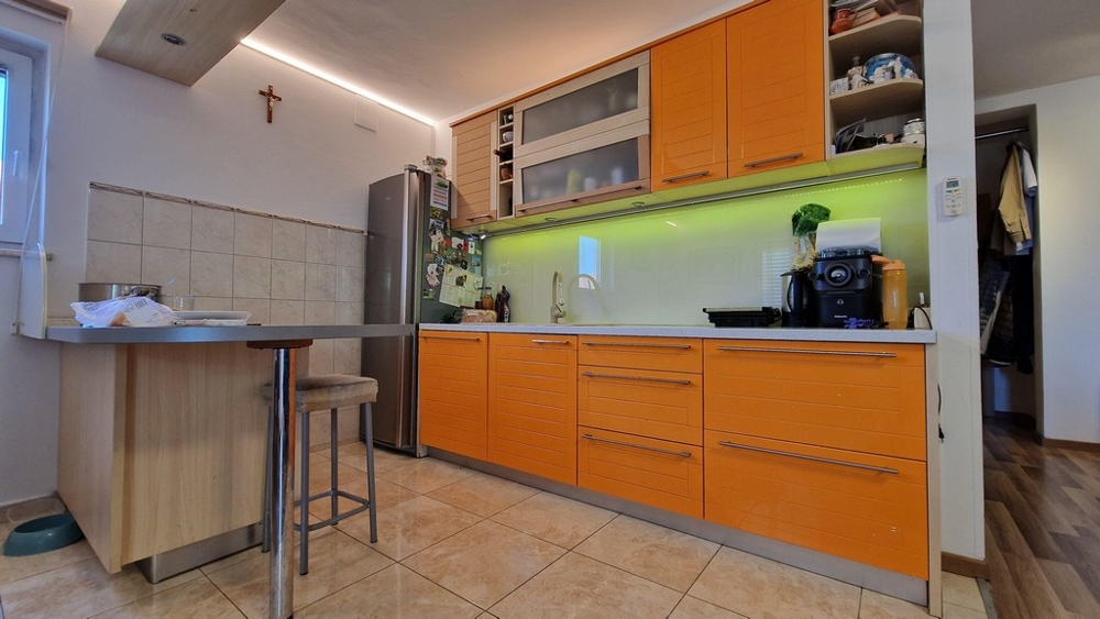 Nowoczesna kuchnia z pomarańczowymi frontami i jadalnią