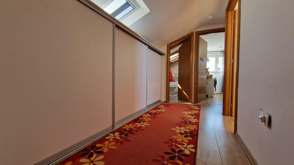 Korytarz z czerwonym dywanem i szafkami pod dachem