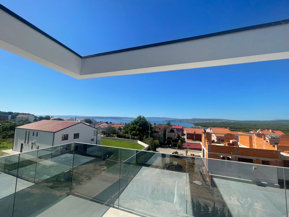 Niedokończony pokój z dużymi szklanymi drzwiami prowadzącymi na taras z widokiem na morze, narzędzia budowlane w pokoju