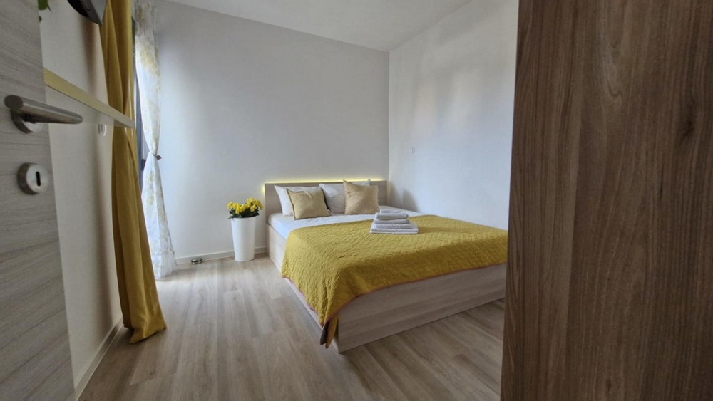 Sypialnia z podwójnym łóżkiem, żółtą kołdrą i dekoracjami