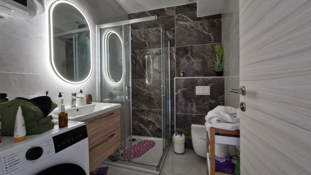 Łazienka z prysznicem, umywalką i pralką