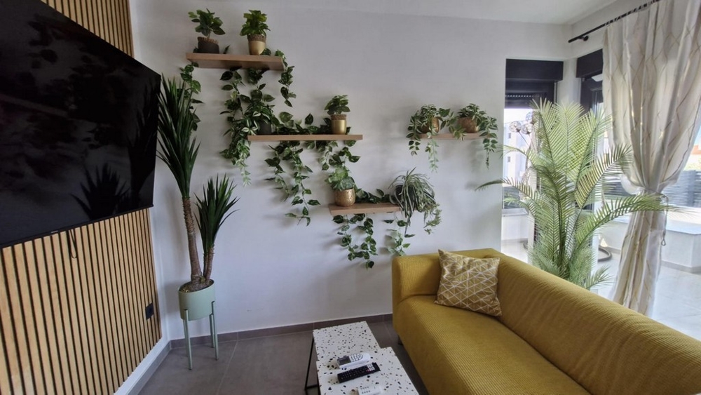 Pokój dzienny z kanapą (żółtą) i TV.