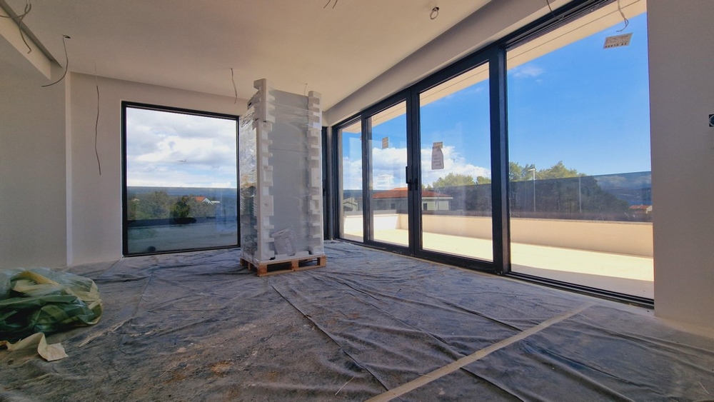 Widok wnętrza nowoczesnego nowego mieszkania z dużymi oknami i widokiem na taras i morze.