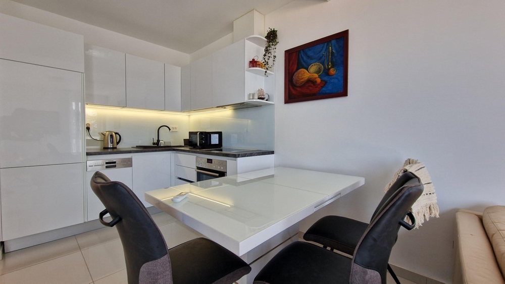 Nowoczesna kuchnia z białym designem na wysoki połysk, jadalnią i przytulnymi meblami.